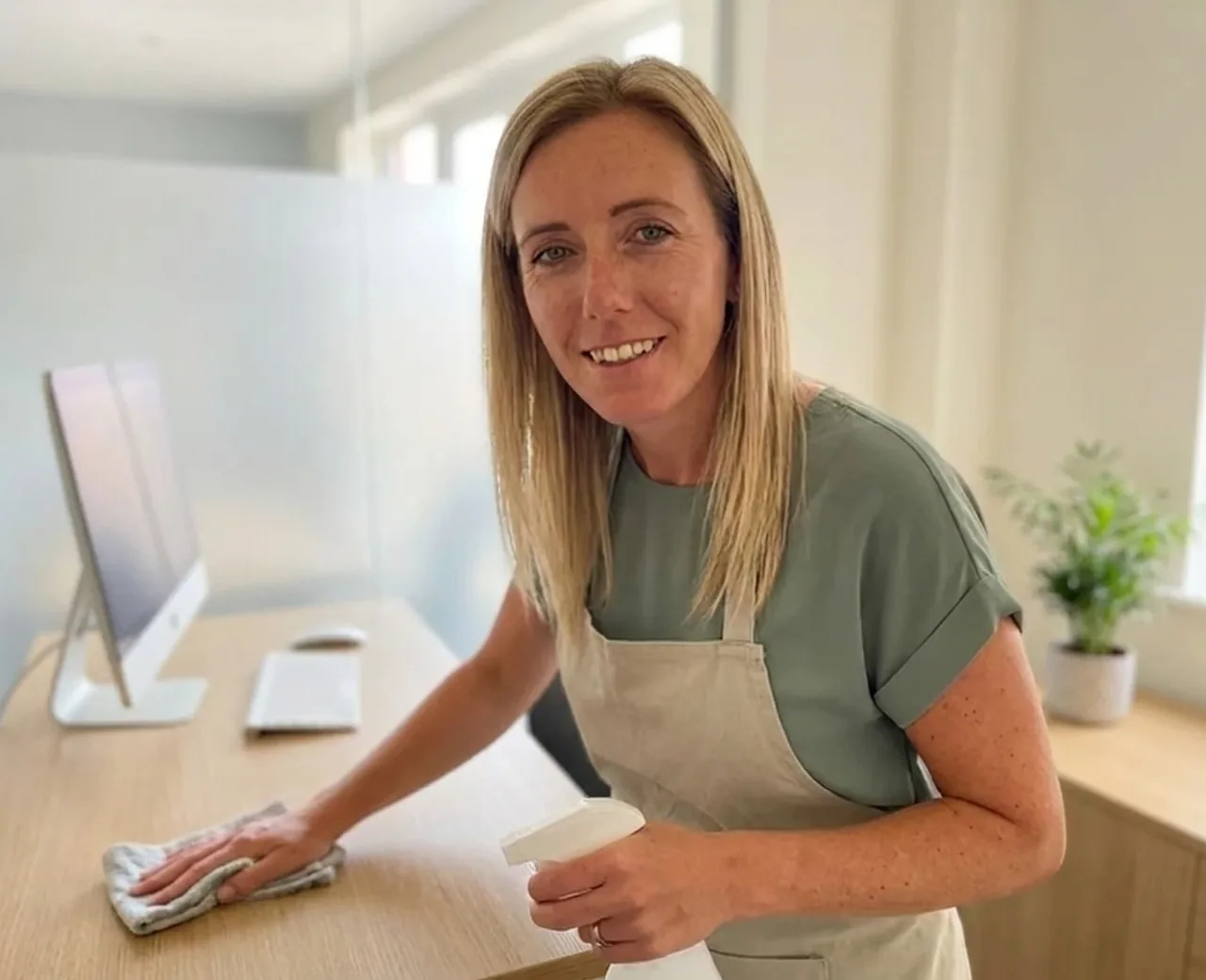 Chantelle wiping down a desk in a small Derby office